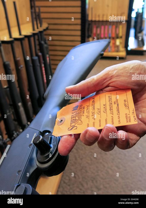 Price tag hanging on a hunting rifle in a gun aisle at a sporting goods store — visually represents MSRP/street price and used-market pricing contexts.